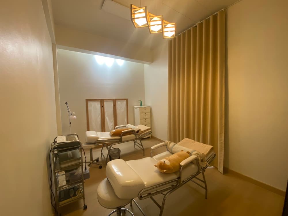 ห้องทำหน้าของ PSC Skincare หล่มสัก มีเตียงทรีตเมนต์สองเตียง ม่านกั้น และรถเข็นวางเครื่องมือ